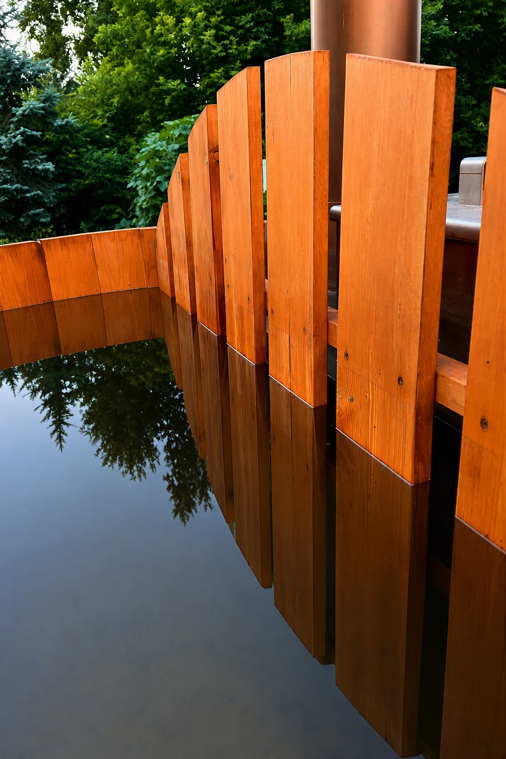 Still water reflecting natural wood panels inside a wood-fired soaking tub